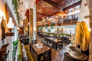 A restaurant with wooden tables, stone walls, and hanging plants. - Hotel Izvora (Kranevo)