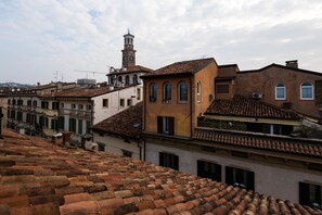 A historic street with terracotta-tiled roofs, traditional architecture, and a prominent tower.