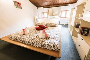 A bedroom with a bed, pillows, a bedside table, a mirror, and a bookshelf.