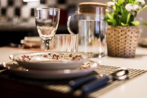 A dining table with a plate, a glass, a pitcher, and a small potted plant.
