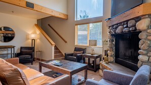 A cozy living room with leather sofas, a fireplace, and a stone accent wall. - Bridgepoint Condo 8 - Freshly Updated, Baldy Views, Walk to Downtown & Lifts (Ketchum)
