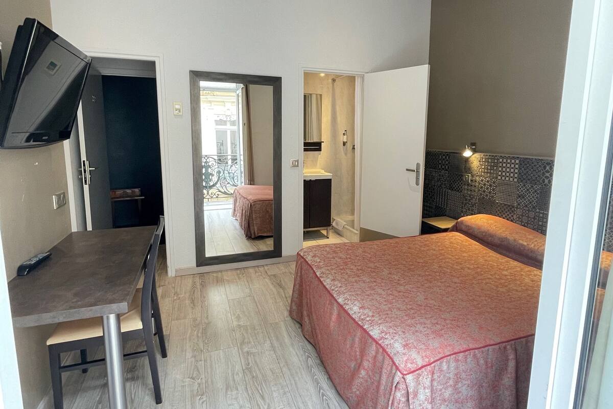 A compact hotel room with a bed, a desk, and a television.
