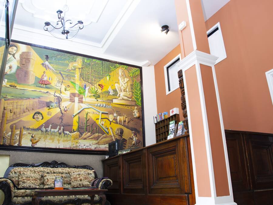 Quarto com um grande mural, um banco de madeira e uma estante com objetos.