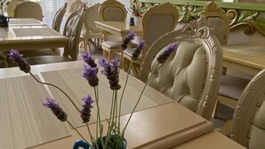 Ein Essbereich mit einem Tisch, gedeckt für vier Personen, mit einer Vase mit violetten Blumen.
