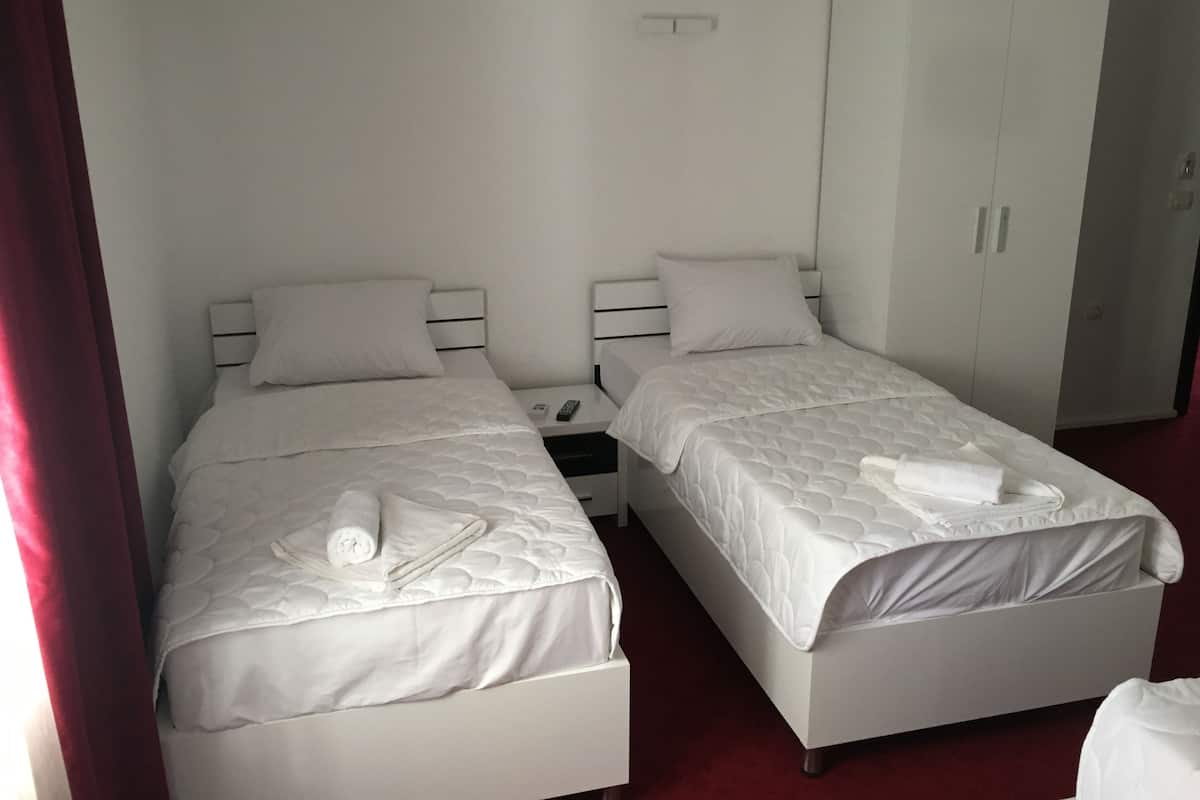 Two single beds with white bedding and a wardrobe in a room.