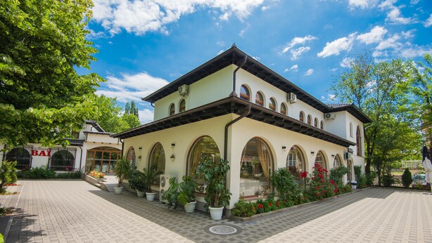 A building with a tiled courtyard, arched windows, and potted plants. - Hotel Camp Karagaq (Pec)