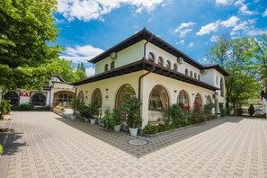 Ein Gebäude mit einem mit Fliesen belegten Innenhof, gebogenen Fenstern und Topfpflanzen.