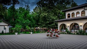 A courtyard with a paved floor, surrounded by trees and a building with arched windows. - Hotel Camp Karagaq (Pec)