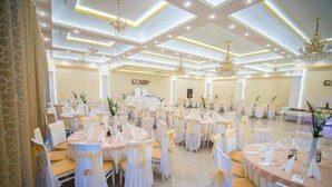 A banquet hall with round tables, white tablecloths, and gold sashes. - Hotel Camp Karagaq (Pec)