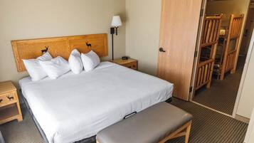 A neatly made bed with a headboard, a bedside table with a lamp, and a bench.