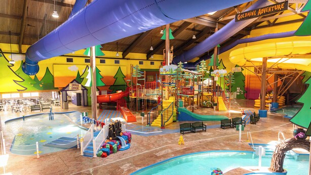 Parque acuático interior con toboganes, piscinas y estructuras de juego.