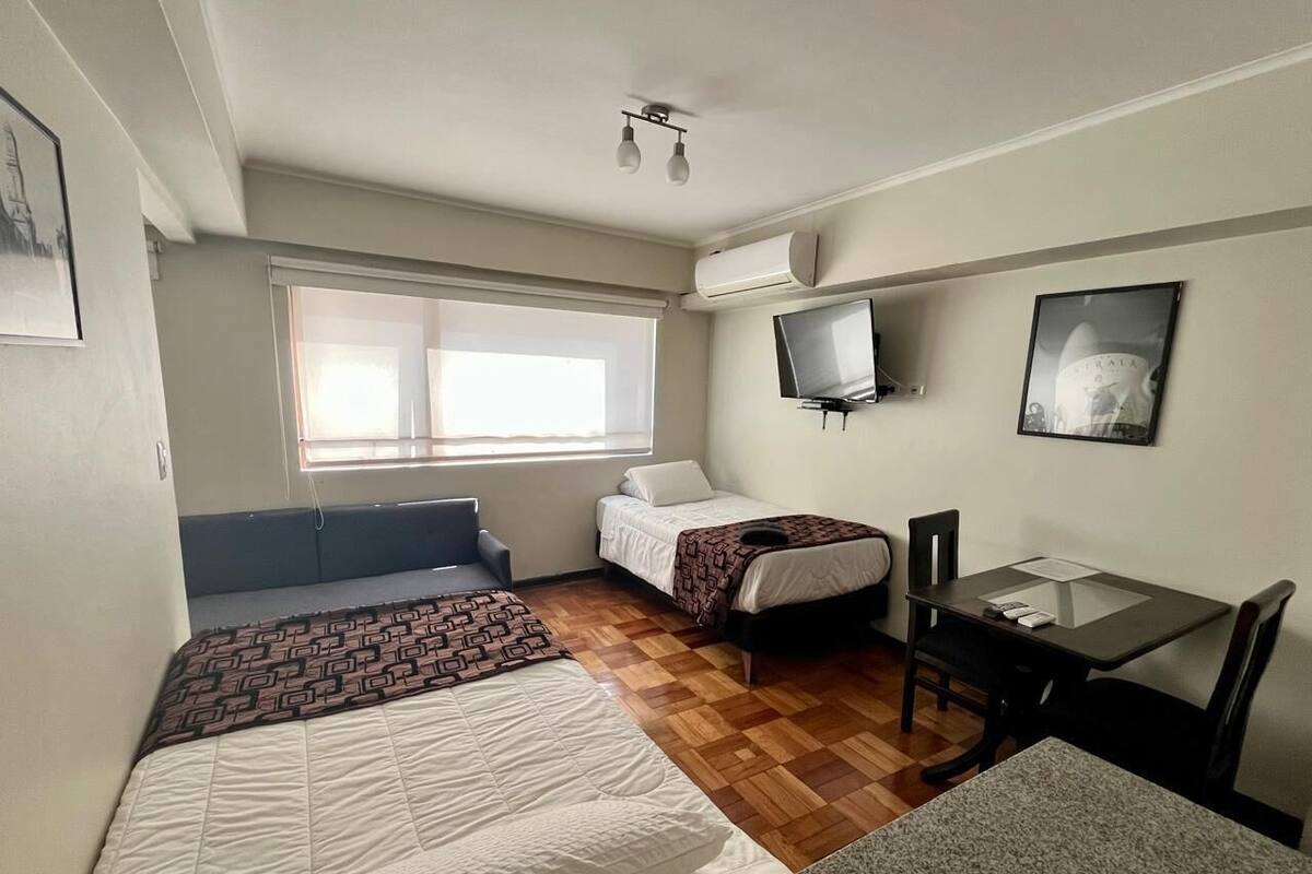 Une chambre avec deux lits, un bureau, une chaise, une télévision et une fenêtre.