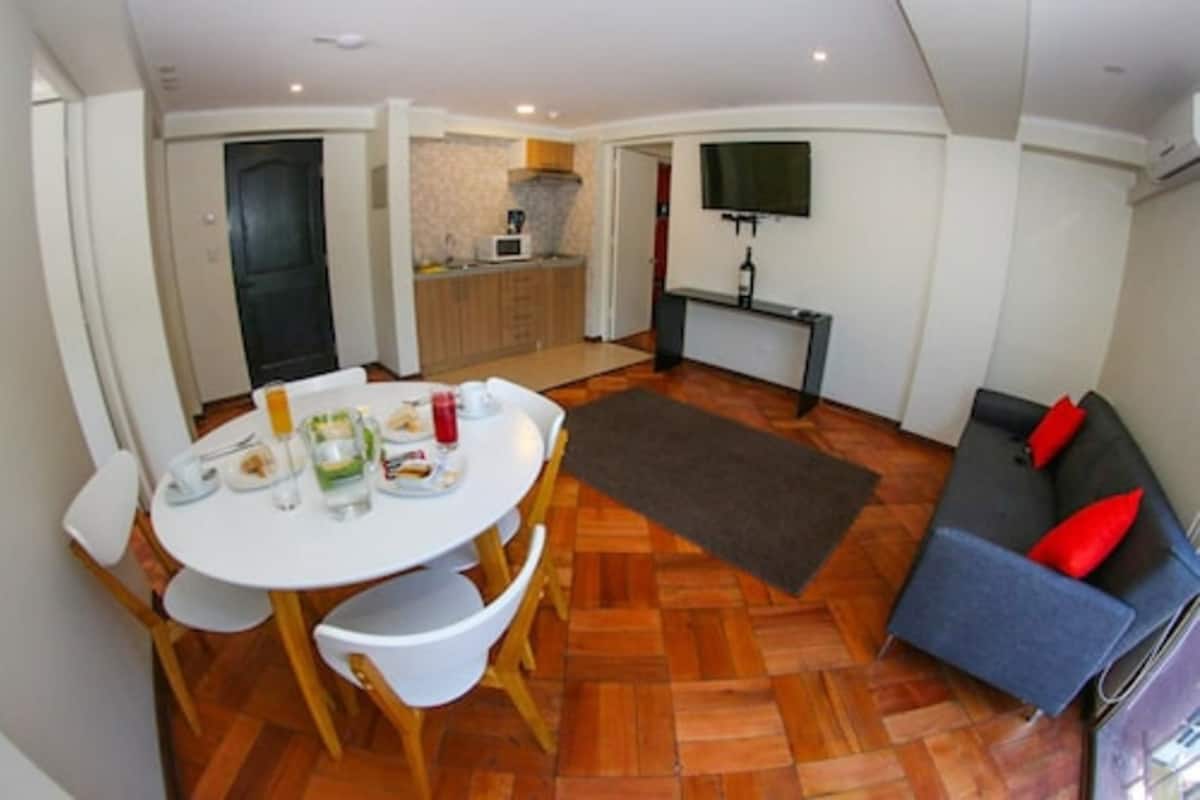 Un espace de vie compact comprenant un coin repas, une kitchenette et un canapé.