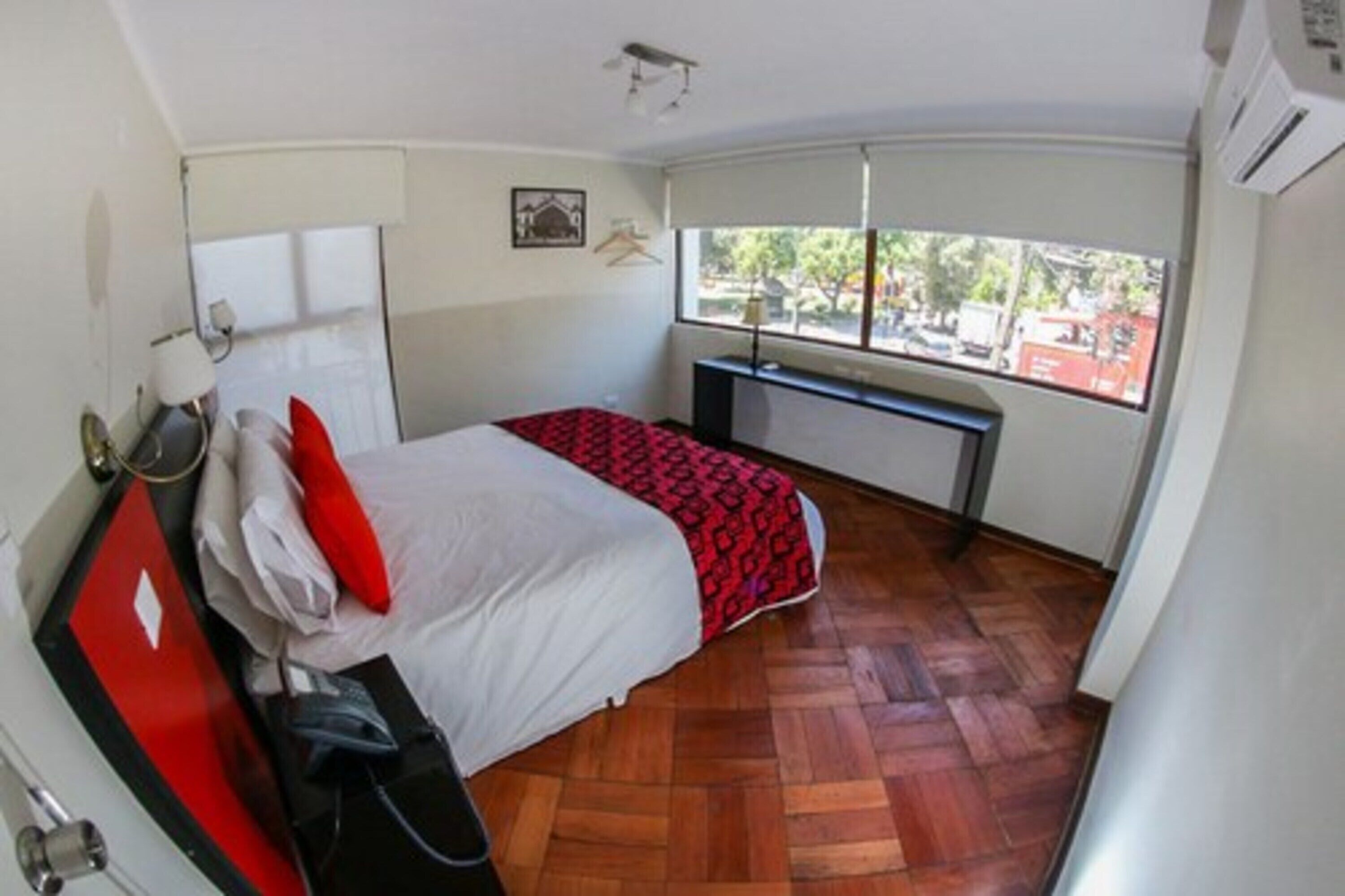 A bedroom with a bed, a desk, and a window.