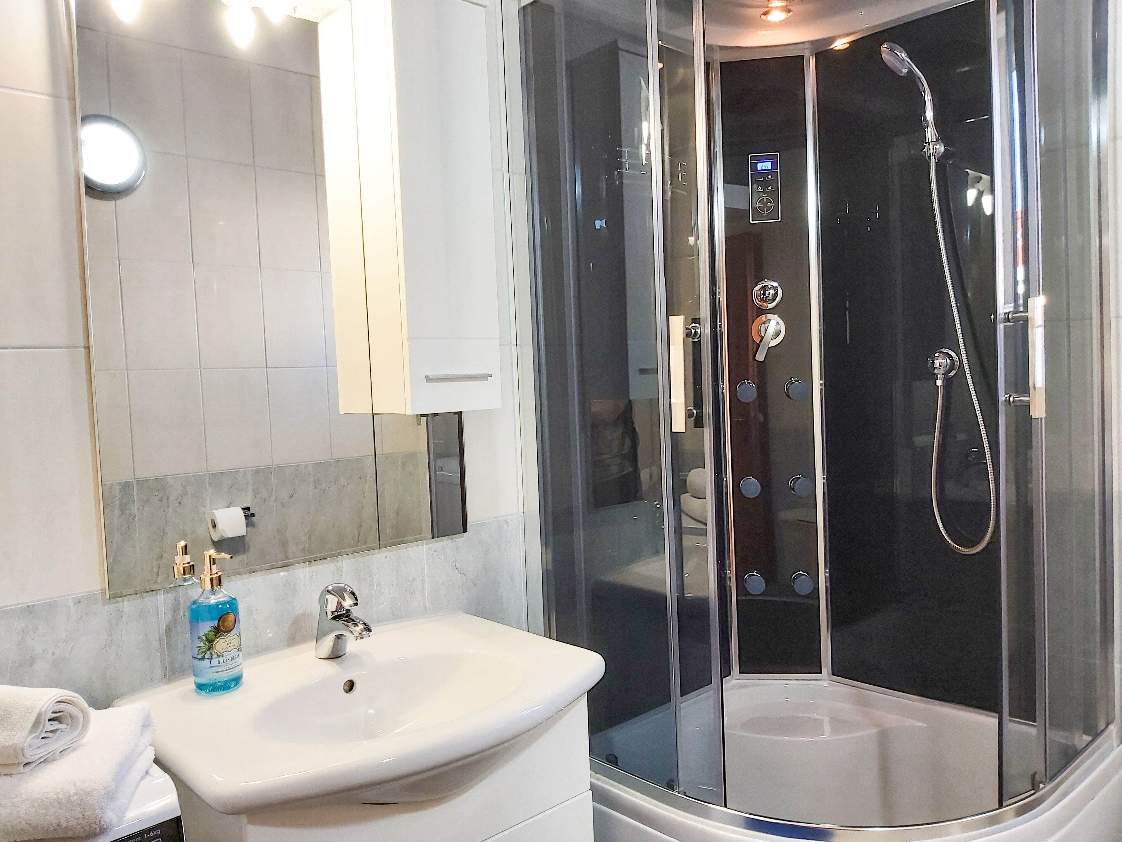 A modern bathroom with a glass-enclosed shower, a white sink, and a mirror above it.