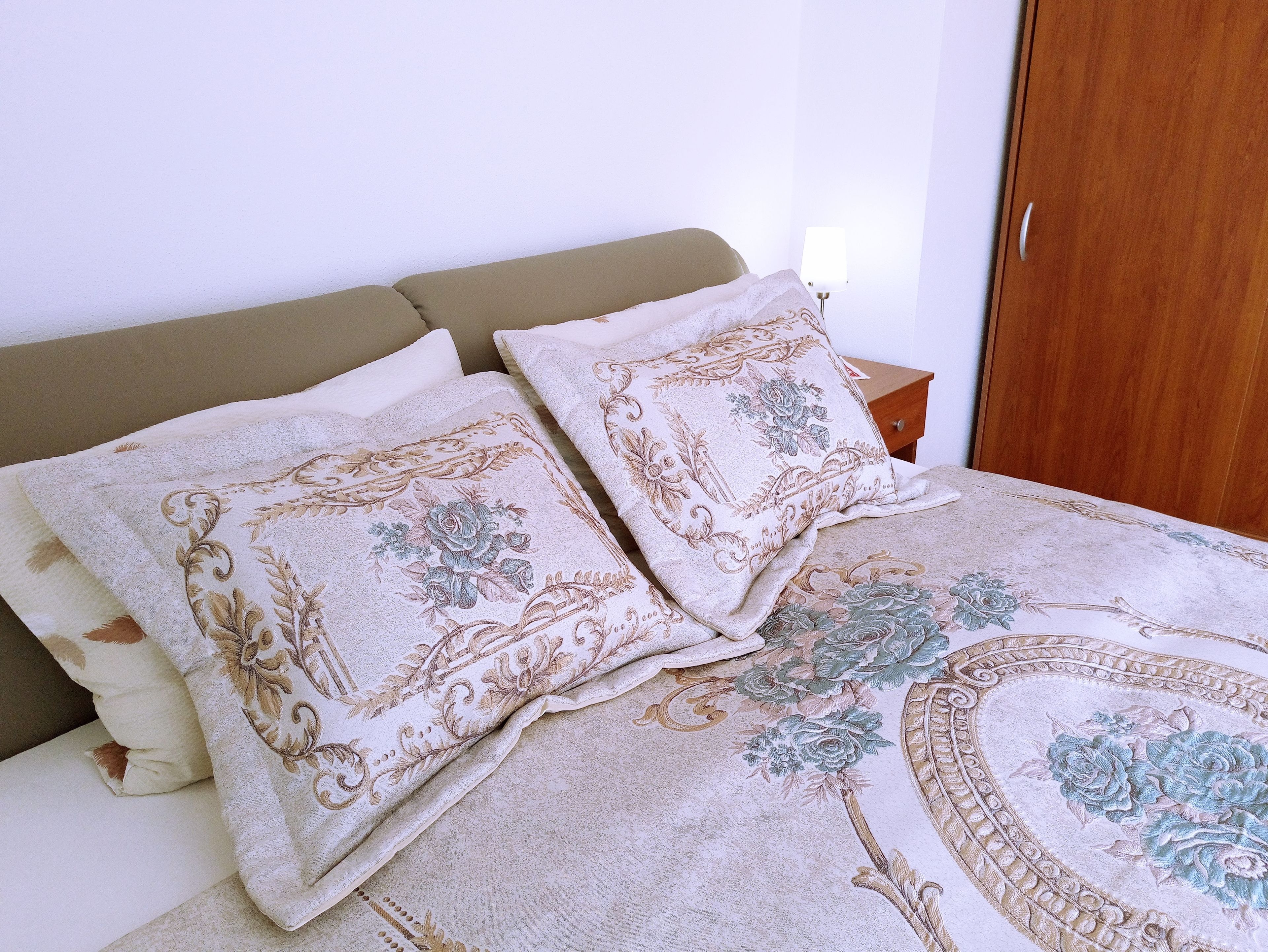 A bed with floral-patterned pillows and a matching duvet.