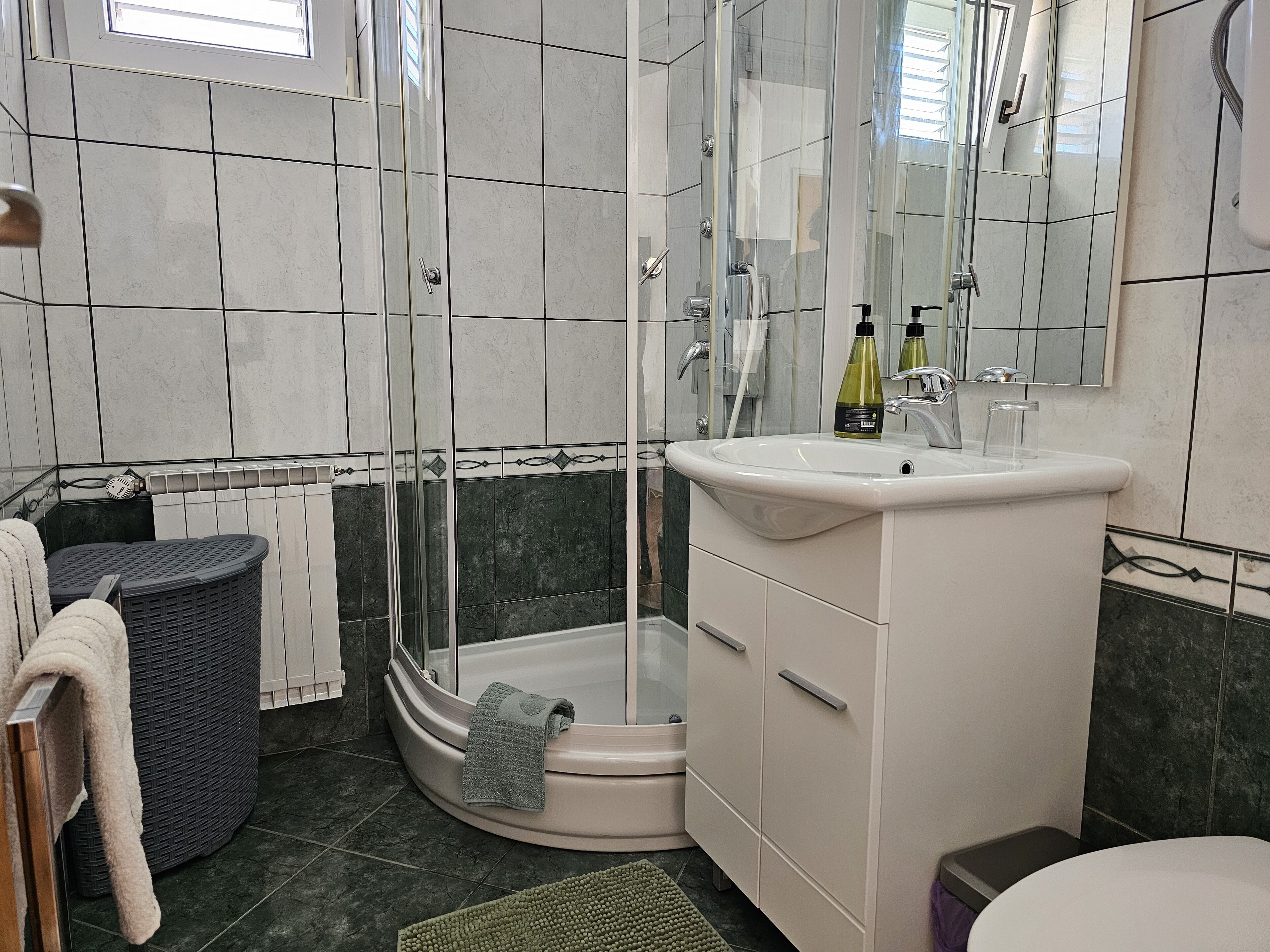 A modern bathroom with a glass-enclosed shower, a white sink, and a corner cabinet.