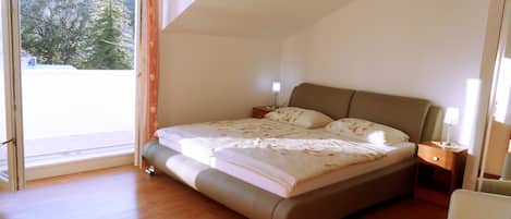 Une chambre à coucher avec un lit, des tables de chevet et une vue sur l’extérieur.