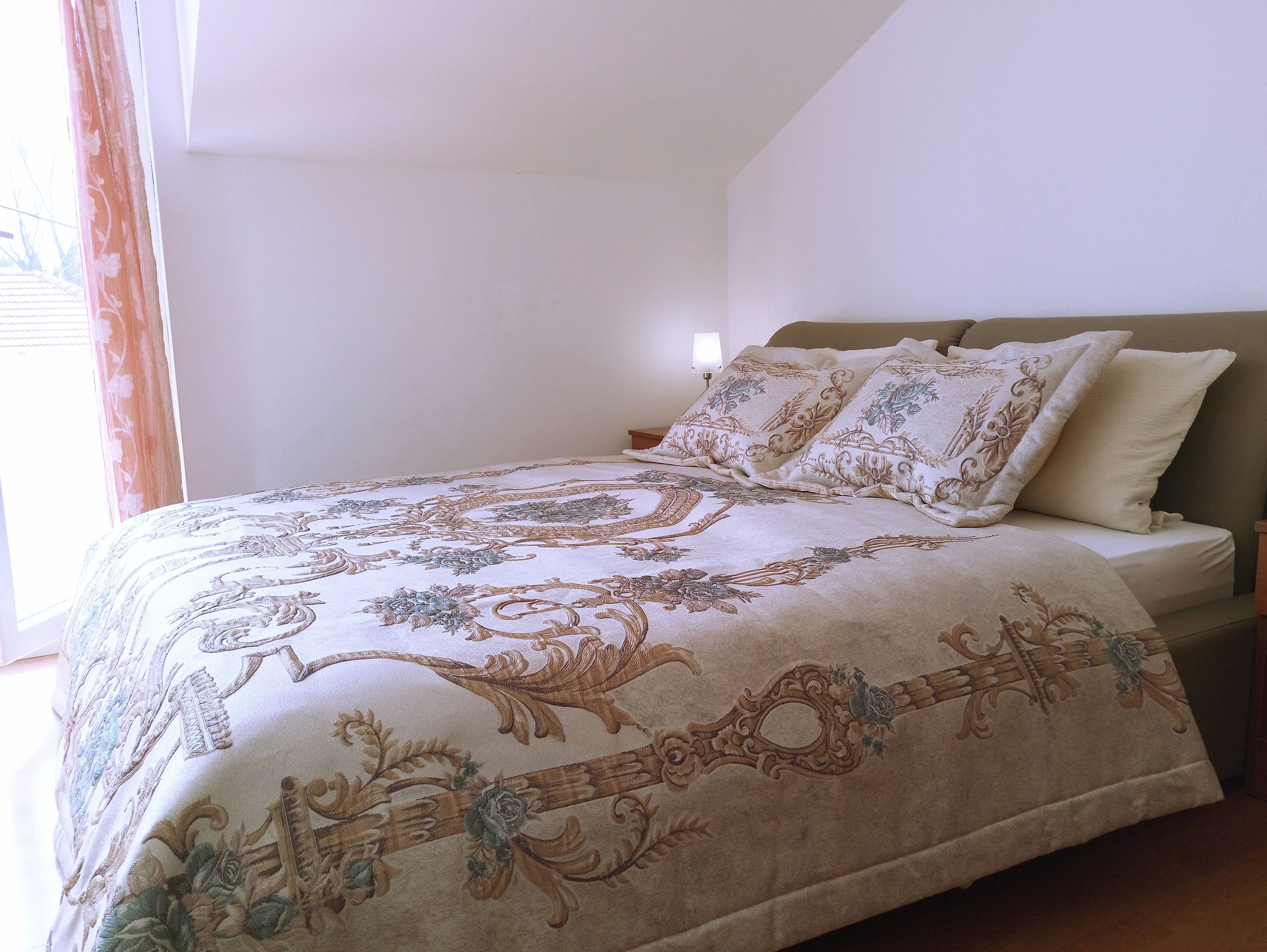 A neatly made bed with a patterned bedspread, a headboard, and two pillows.