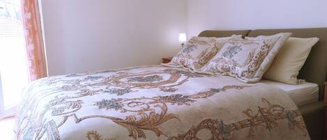 Uma cama bem arrumada com colcha estampada, cabeceira e dois travesseiros.