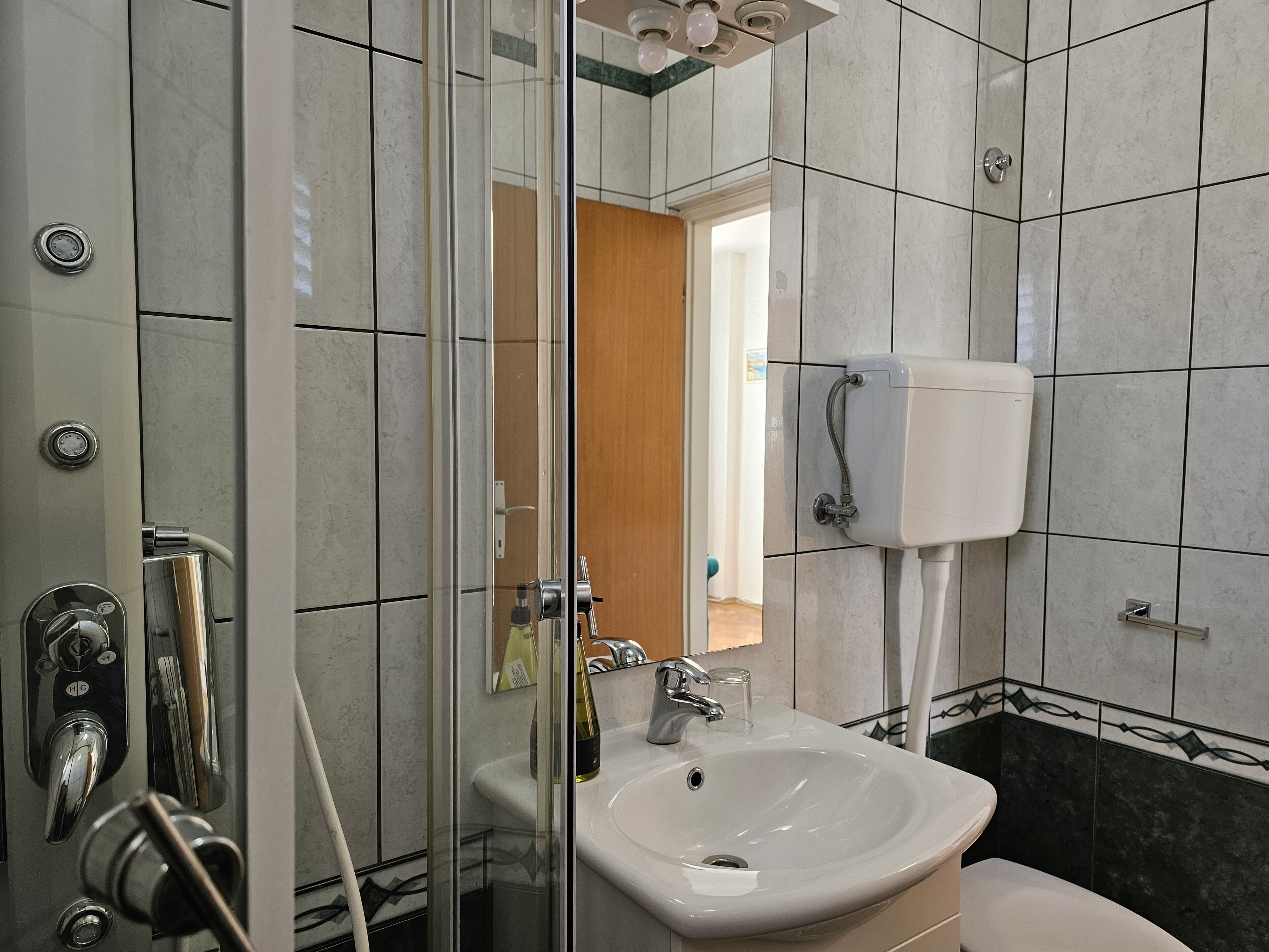 A bathroom with a glass shower enclosure, a sink, and a toilet.