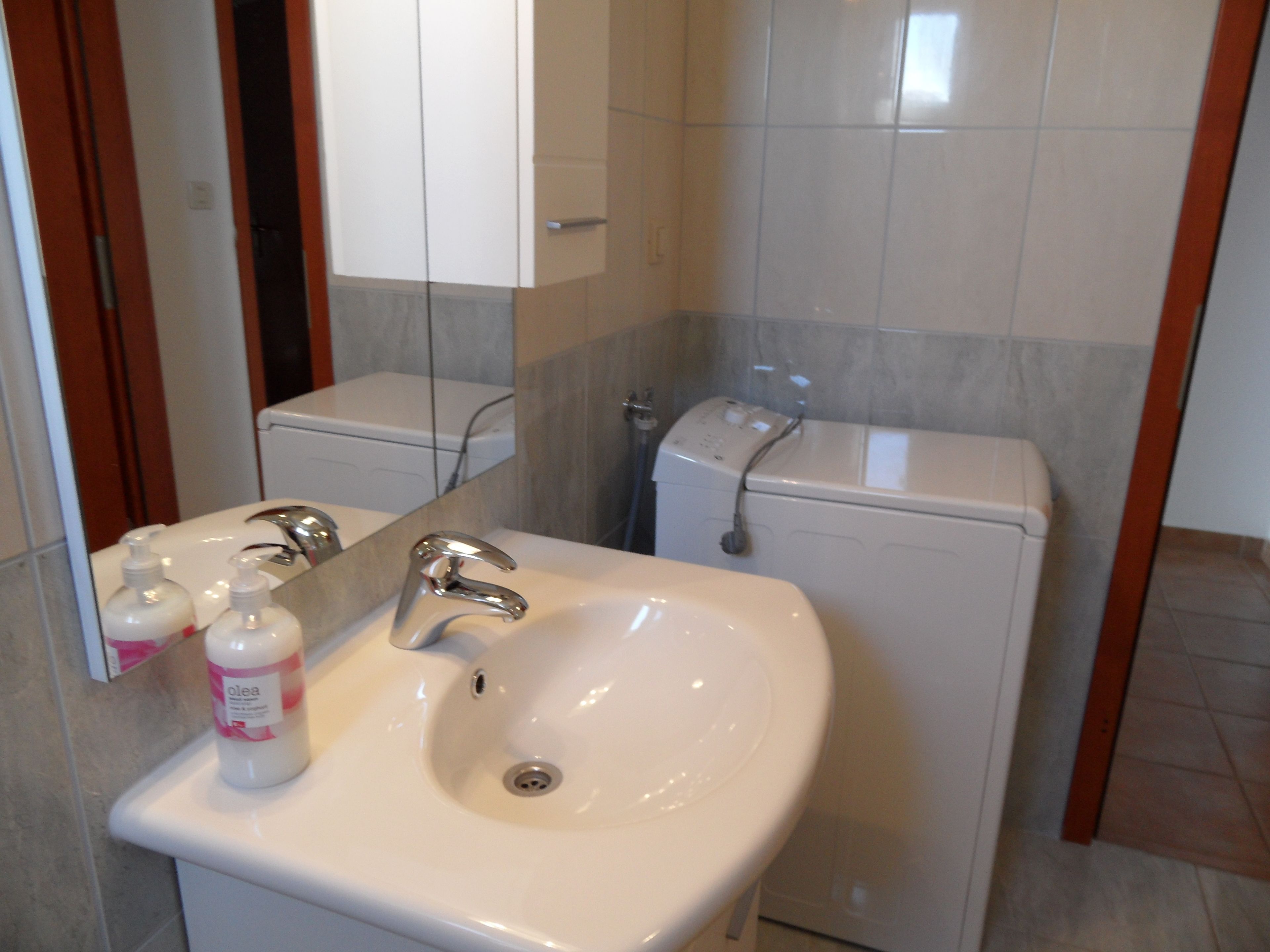 A bathroom with a white sink, mirror, and toilet.