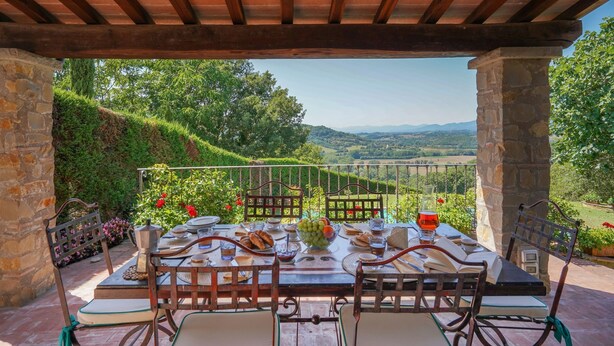 A covered outdoor dining area with a table set for two, surrounded by stone walls and a view of rolling hills. - Stunning private villa for 4 guests with A/C, private pool, WIFI, TV, patio and panoramic view (Vicchio)