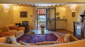 A cozy living room with a sofa, armchairs, a coffee table, and a view of the outdoors through a door. - Stunning private villa for 4 guests with A/C, private pool, WIFI, TV, patio and panoramic view (Vicchio)