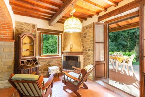 A rustic interior with a stone fireplace, wooden furniture, and a view of the outdoors.