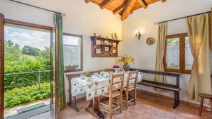 A dining area with a table set for four, wooden chairs, a bench, and a view of greenery outside. - Wonderful private villa for 7 guests with private pool, WIFI, TV, balcony and panoramic view (Pilarciano)