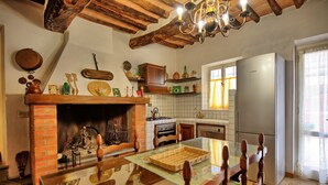 A kitchen with a brick fireplace, wooden ceiling beams, and a modern refrigerator. - Villa Buonaparte - Vacation rental near Pisa, Tuscany (Corazzano)