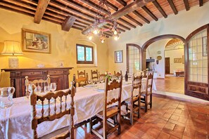 A dining area with a long wooden table set for a meal, surrounded by chairs.