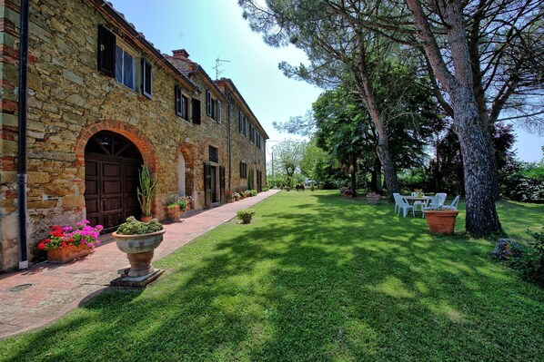 A stone building with arched doorways, a paved walkway, and outdoor seating.