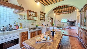 Une cuisine spacieuse avec un grand îlot central en bois, un dosseret de carrelage blanc et un plafond en bois rustique.