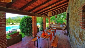 Une terrasse extérieure avec une piscine, des tables en bois et un canapé.
