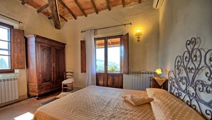 Un dormitorio con una cama grande, un armario de madera y una ventana con vistas.