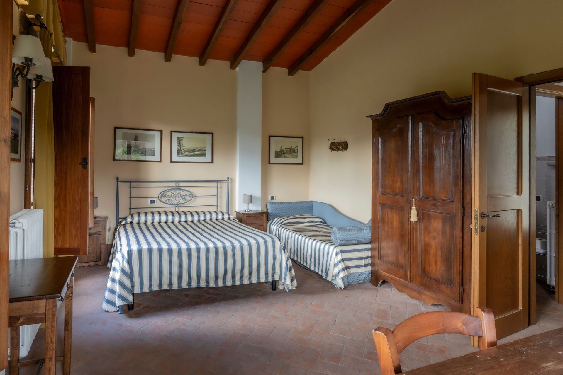 Une chambre avec deux lits, une armoire en bois, un radiateur et une chaise.