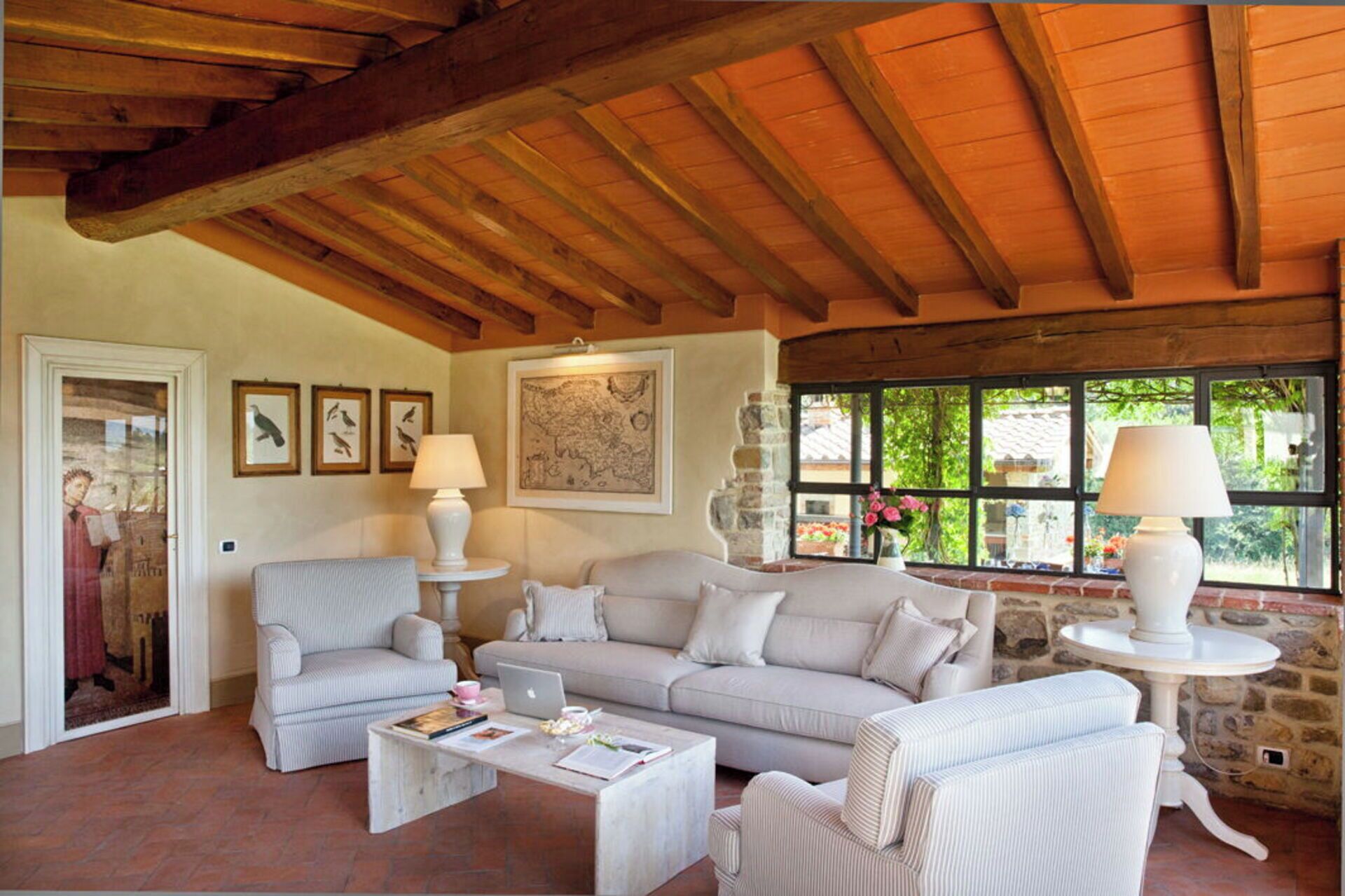 Ein gemütliches Wohnzimmer mit Steinwand, Holzboden und einem großen Fenster mit Blick auf Grünflächen.