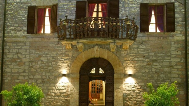 A stone building with a balcony, an arched entrance, and potted plants. - Villa Gubbio - Luxury Villa Rental with private swimming pool in Gubbio, Umbria (Gubbio)