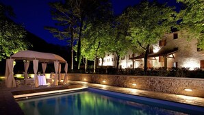 A swimming pool with a covered seating area and a stone wall. - Villa Gubbio - Luxury Villa Rental with private swimming pool in Gubbio, Umbria (Gubbio)