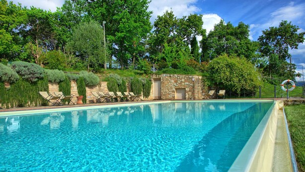 A clear swimming pool with lounge chairs and a stone wall. - Le Fonti 5 - Apartment with swimming pool (Grassina)