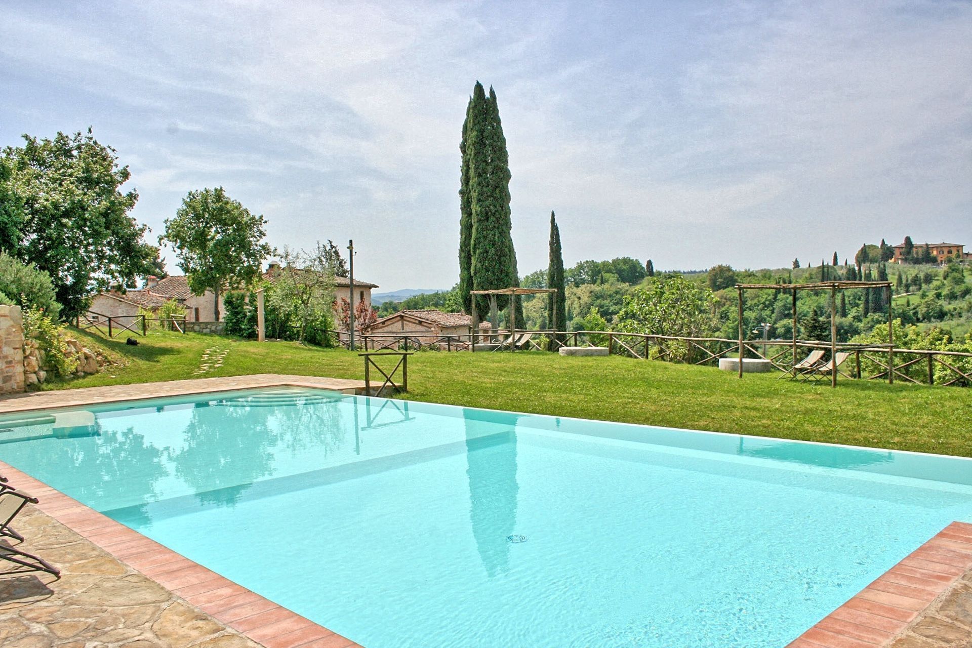 Une piscine rectangulaire à l’eau d’un bleu limpide, entourée d’une terrasse en pierre.