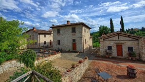 A courtyard with stone buildings, outdoor seating, and potted plants. - Le Fonti 5 - Apartment with swimming pool (Grassina)