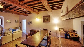A rustic dining area with a wooden table and chairs, a sofa, and a painting on the wall. - Pozzo dei Desideri 2 - Apartment with swimming pool (Mercatale)