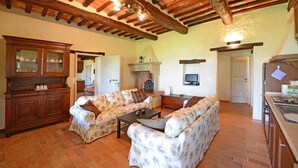Una sala rústica con vigas de madera a la vista, una chimenea y un gran aparador de madera.