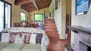 A cozy living room with a sofa, a fireplace, and a staircase leading to another room. - Villa Ulivi - Holiday Country Villa in Lucignano, Valdichiana, Tuscany (Lucignano)