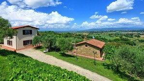 A two-story house with a red roof, surrounded by lush greenery and a gravel path. - Villa Ulivi - Holiday Country Villa in Lucignano, Valdichiana, Tuscany (Lucignano)