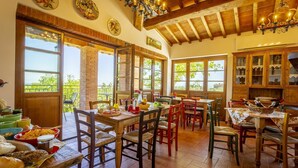 Un coin repas rustique avec des tables et des chaises en bois, de grandes fenêtres et une vue sur la verdure environnante.