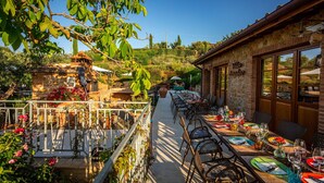 Un espace de restauration en plein air avec des tables et des chaises, un bâtiment en pierre et une vue sur le paysage environnant.
