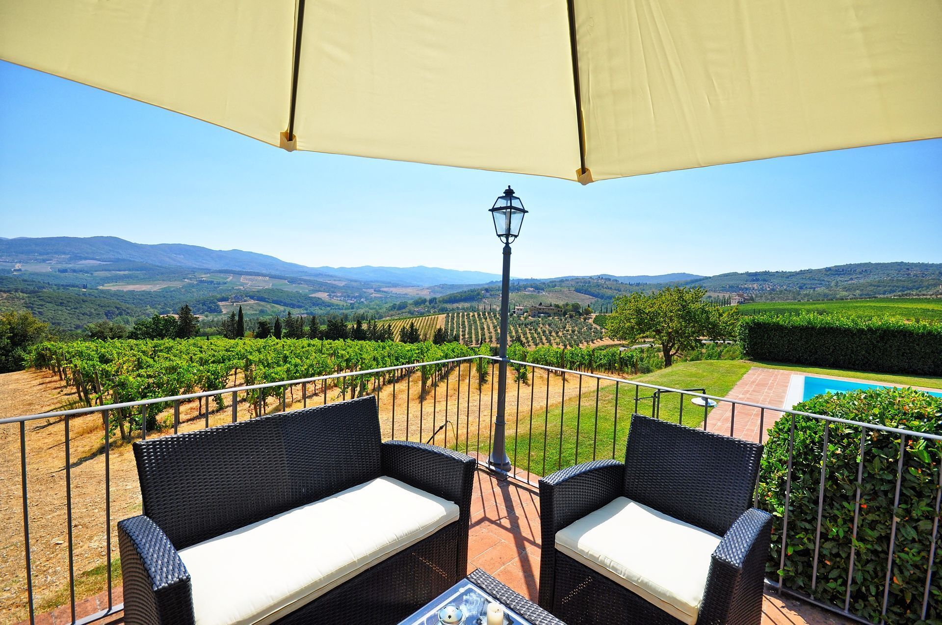 A terrace with wicker furniture, a pool, and a vineyard view.